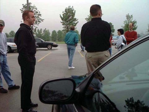 2000 Ford Crown Victoria - A black 2000 Ford Crown Victoria is seen parked in a lot with several people around.