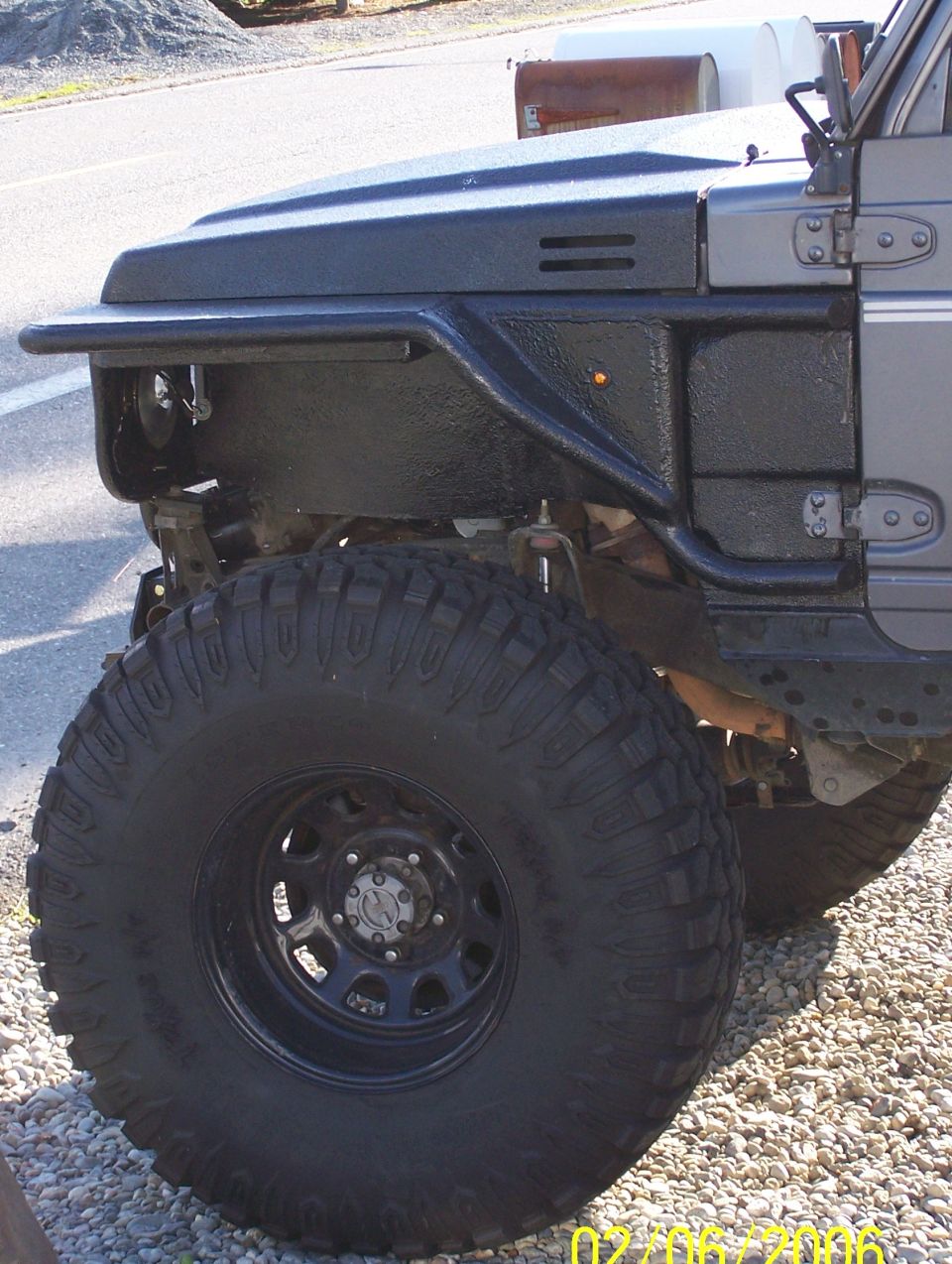 Cut and tubed front fender of a lifted Suzuki 4x4 with black coating and large mud-terrain tire