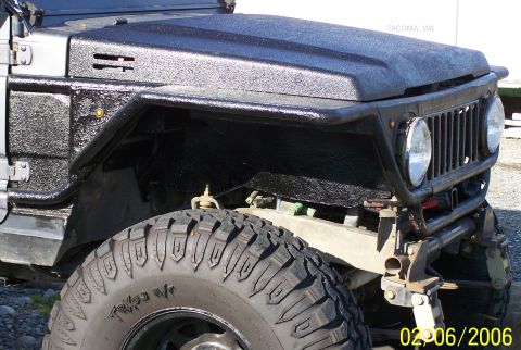 1988 Suzuki Samurai - Close-up of a Suzuki Samurai's front end, showing the textured paint on the fender and hood.