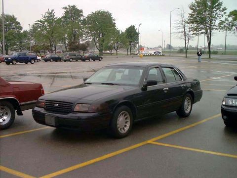2000 Ford Crown Victoria - Black 2000 Ford Crown Victoria parked in a lot with other vehicles visible.