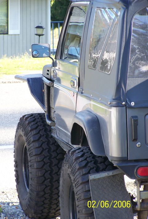 1988 Suzuki Samurai - This modified Suzuki Samurai features aggressive off-road tires and a dark soft top, seen from its rear three-quarter side.