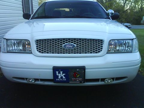 2003 Ford Crown Victoria - The front grille and headlights of a white Ford Crown Victoria are visible, along with a license plate frame.