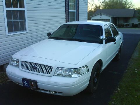 2003 Ford Crown Victoria - A white 2003 Ford Crown Victoria is parked in front of a house.