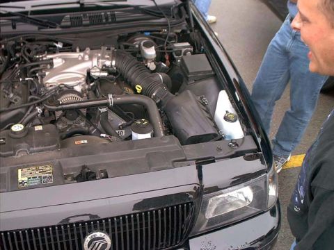 2000 Ford Crown Victoria - The engine bay of a 2000 Ford Crown Victoria is shown, with the V8 engine and front grille in view.