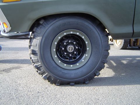 1978 Ford Bronco - The front wheel and fender of a 1978 Ford Bronco are visible, with another vehicle in the background.