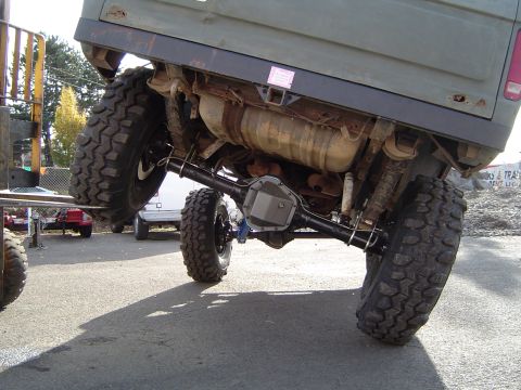 1978 Ford Bronco - The rear axle and suspension components of a heavily modified vehicle are visible, with a pink sticker on the frame.