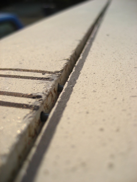 1989 Ford Bronco - The detail of a panel gap on a vehicle is shown, with a blurred blue vehicle in the background.