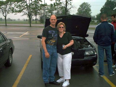 2000 Ford Crown Victoria - Couple poses with a 2000 Ford Crown Victoria, hood up, showing the engine bay.