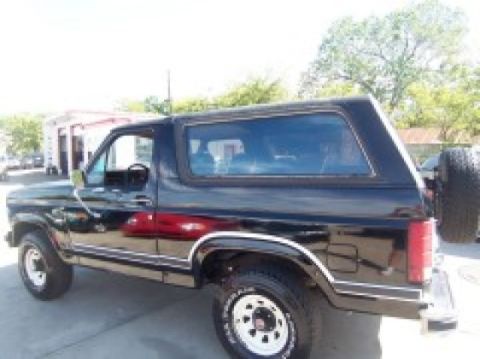 1986 Ford Bronco - Side view of a black 1986 Ford Bronco parked outdoors.
