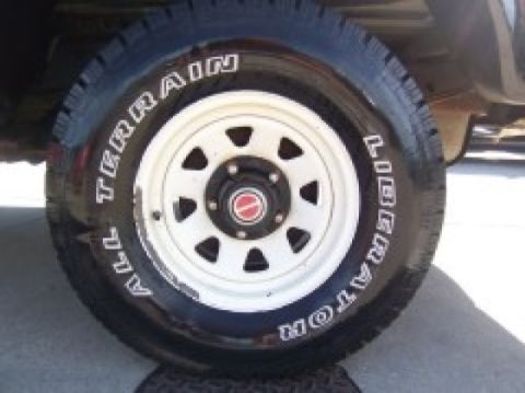 1986 Ford Bronco - A close-up view of a tire and wheel assembly, with visible white lettering on the tire's sidewall.