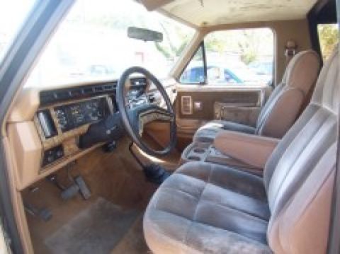 1986 Ford Bronco - The interior of a 1986 Ford Bronco features a tan dashboard, plush seats, and a prominent steering wheel.