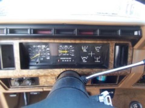 1986 Ford Bronco - The dashboard shows a speedometer, tachometer, and other warning lights, with a prominent steering wheel.