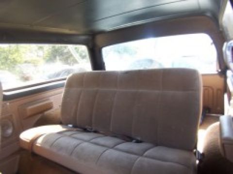 1986 Ford Bronco - The interior of a 1986 Ford Bronco is visible, a bench seat and windows looking out to a sunny day.