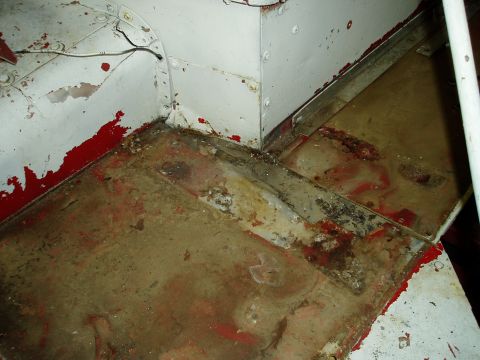 2000 Ford E350 - The interior floor and wall junction shows significant wear, rust, and peeling paint.