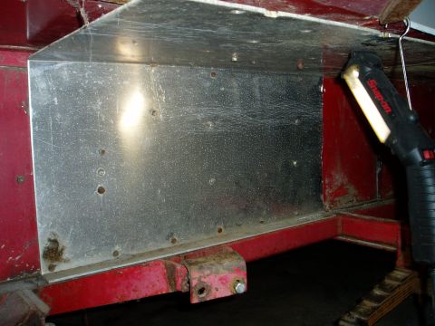 2000 Ford E350 - Close-up of a metal panel attached to a red frame, illuminated by a work light.