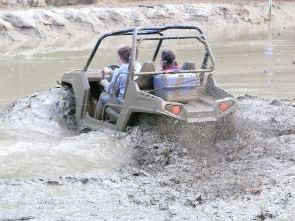 Gray UTV driving through mud, rear view