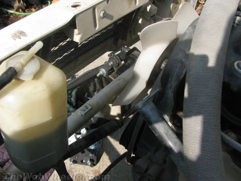 1987 Suzuki Samurai - Engine bay components are visible, including a fan, hoses, and a fluid reservoir with dark fluid.