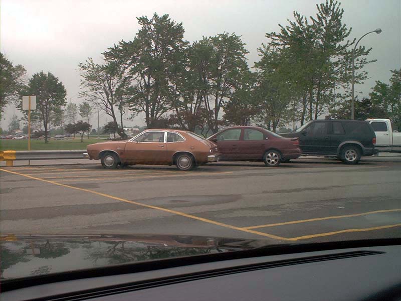 Brown coupe parked next to a red sedan and black SUV