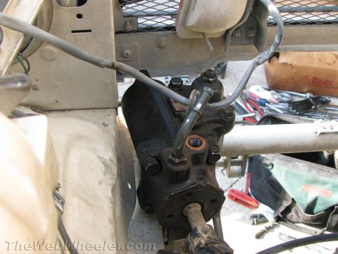 1987 Suzuki Samurai - A close-up view of a vehicle's power steering gearbox and associated hoses, with tools visible in the background.