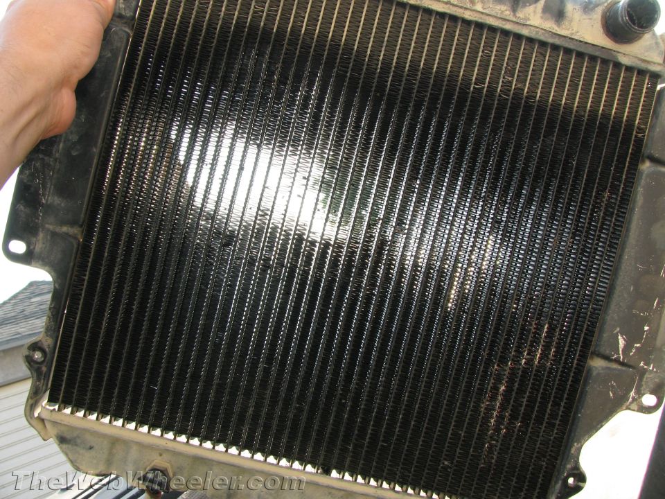 Radiator with black fins and metal frame, held by a hand