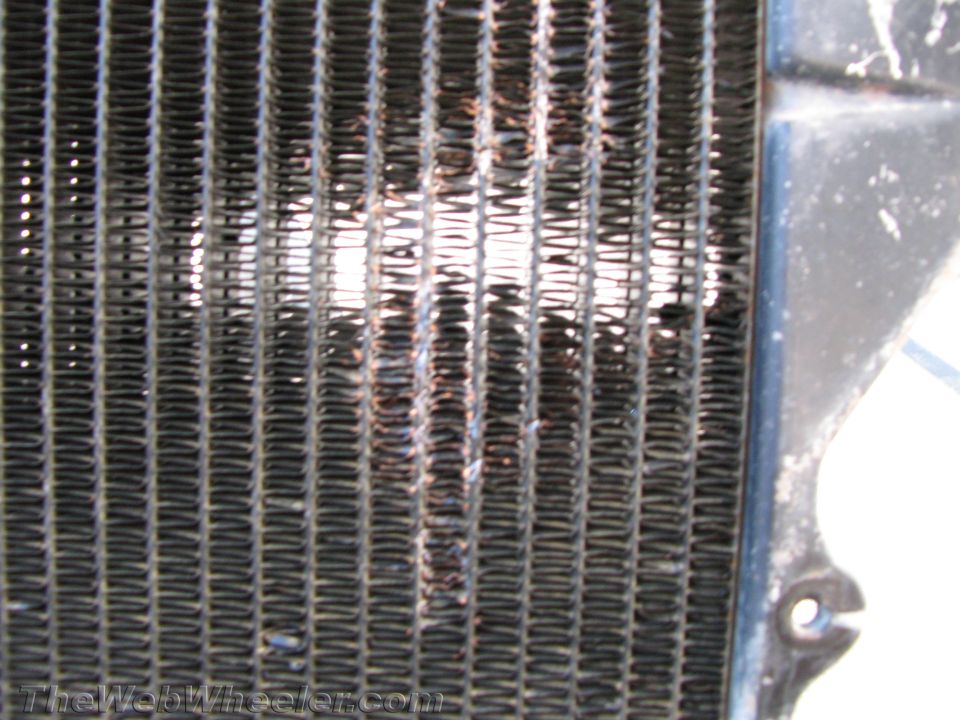 Close-up of a damaged radiator grille with bent fins