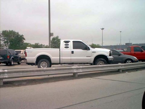 2000 Ford Crown Victoria - White Ford F-Series truck seen from the side, parked in a lot with other vehicles.