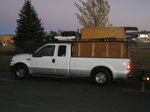 1989 Ford F-350 - This pickup truck, likely a late 1990s model, is equipped with a wooden bed insert and a roof rack, suggesting it's used for hauling.