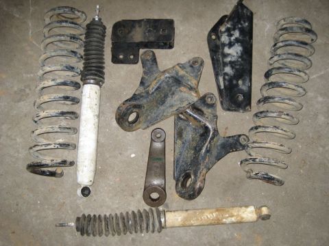1995 Ford Bronco - Various used suspension parts laid out on a concrete surface.