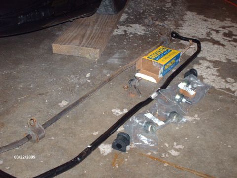1995 Ford Probe - Car parts laid out on a concrete floor, including sway bars and a box of Moog components.