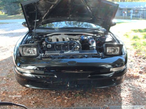 1995 Ford Probe - Front view of a black 1995 Ford Probe with the hood open, revealing the engine compartment.