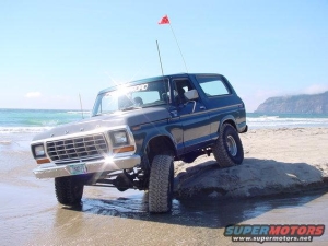 1986 Ford Bronco - A dark blue 1978 Ford Bronco is positioned on a rock near the ocean on a sunny day.