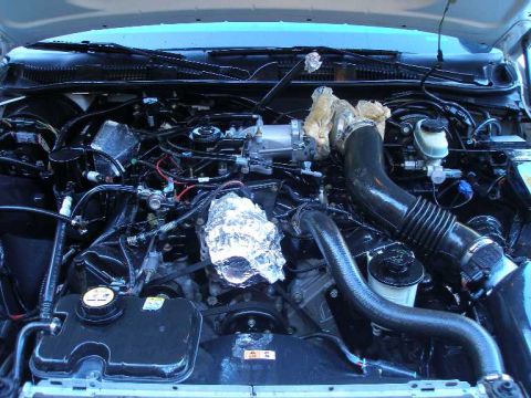 2001 Ford Crown Victoria - Engine bay of a 2001 Ford Crown Victoria, with some components covered in foil for cleaning or detailing.
