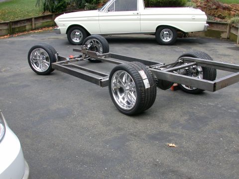 1964 Ford Ranchero - Custom chassis with chrome wheels sits in front of a 1964 Ford Ranchero.