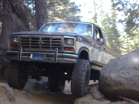 1985 Ford Bronco - This Ford Bronco is navigating a rocky trail with large boulders on either side.
