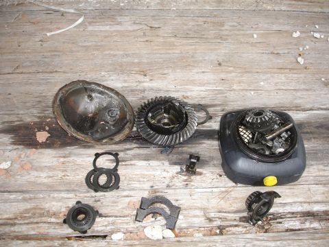 1989 Ford Bronco - Disassembled differential parts are laid out on a weathered wooden surface, showing various gears and housing components.