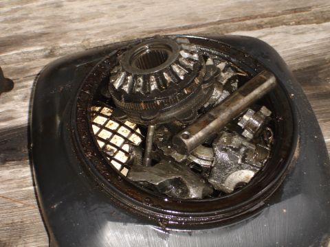1989 Ford Bronco - Close-up view of damaged differential gears and associated components within a black housing, resting on a wooden surface.