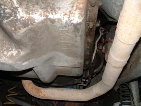 1995 Ford Bronco - Close-up view of the undercarriage of a vehicle, focusing on the exhaust system and transmission.