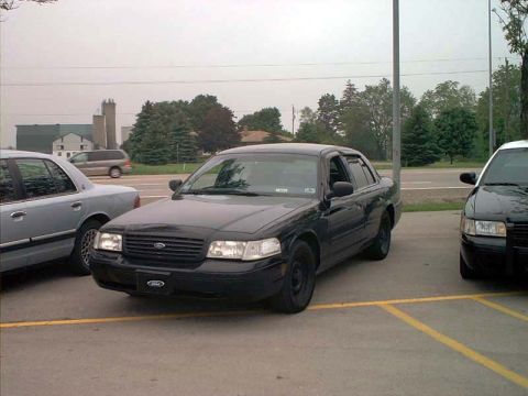 2000 Ford Crown Victoria - A black Ford Crown Victoria is parked in a lot, with other vehicles nearby.