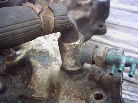 1979 Ford LTD - Engine part with hoses and a green plastic vacuum fitting, likely from an older vehicle.