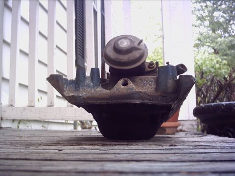 1979 Ford LTD - An intake manifold with a vacuum actuator is shown resting on a wooden deck.