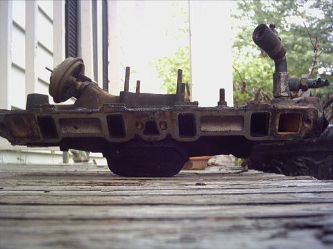 1979 Ford LTD - This is a used engine intake manifold with various pipe fittings and a vacuum actuator attached.