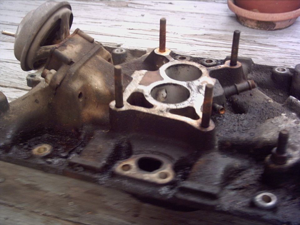 Close-up of a dirty engine intake manifold with bolts and vacuum lines