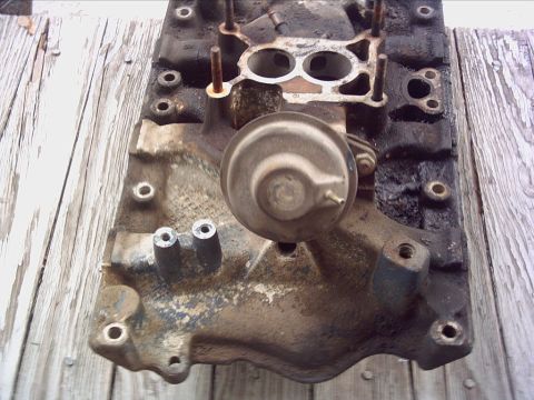 1979 Ford LTD - A used intake manifold with visible dirt and grime, mounted on a wooden surface.