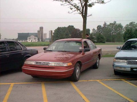 2000 Ford Crown Victoria - A red sedan is parked in a lot, showing its front 3/4 view. The vehicle's body style suggests it is a 1998 model.
