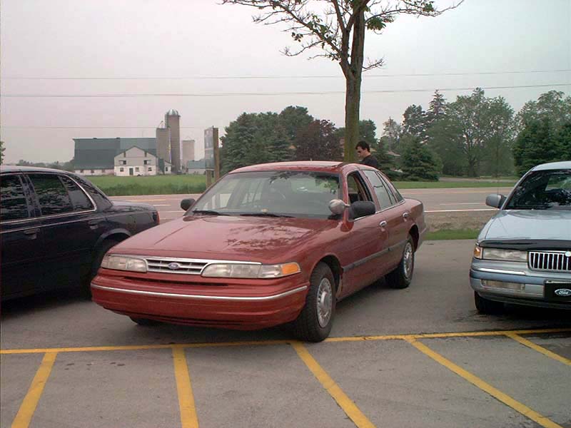 Red sedan parked in a lot, front 3/4 view. Appears to be a 1998 model