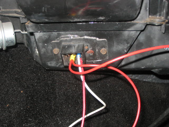 Rocker switch on black under-dash housing with red and white wires and crimp connectors above dark carpet
