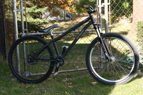 1997 Ford Probe - A black Specialized mountain bike is parked on grass next to a fence.