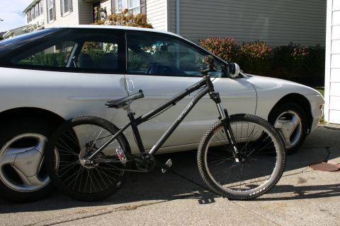 1997 Ford Probe - A bicycle is parked next to a white car in a driveway.