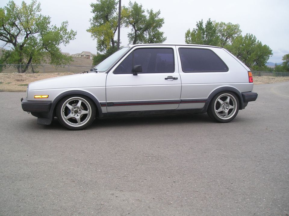 Silver hatchback car with tinted windows and aftermarket wheels, seen from the side