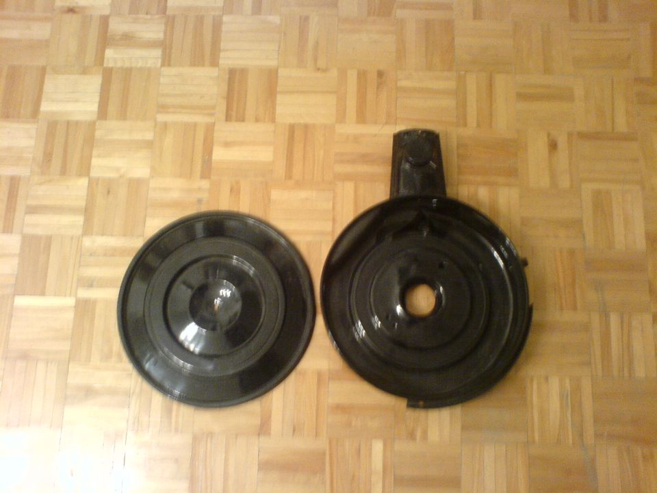 Two black air cleaner housings on a wood floor